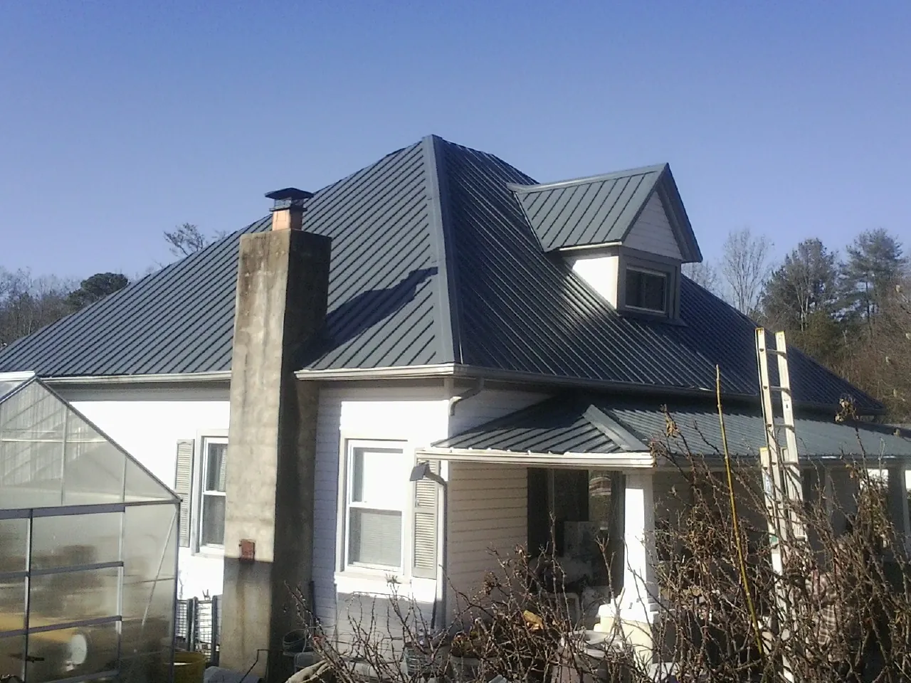Dark blue standing seam metal roof on a white farmhouse with dormer — Slate & Tile Roof Repair by Roofing Brothers in Mountain Lakes