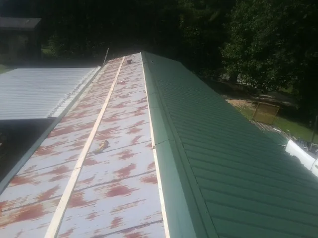 Old rusted panels beside newly installed green metal roofing — Wind Damage Roof Repair by Roofing Brothers in Mountain Lakes