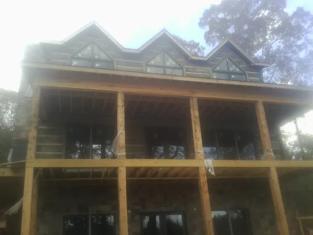 Dormers and porch framing on a large log home under construction — Roof Coating work by our crew in Mountain Lakes