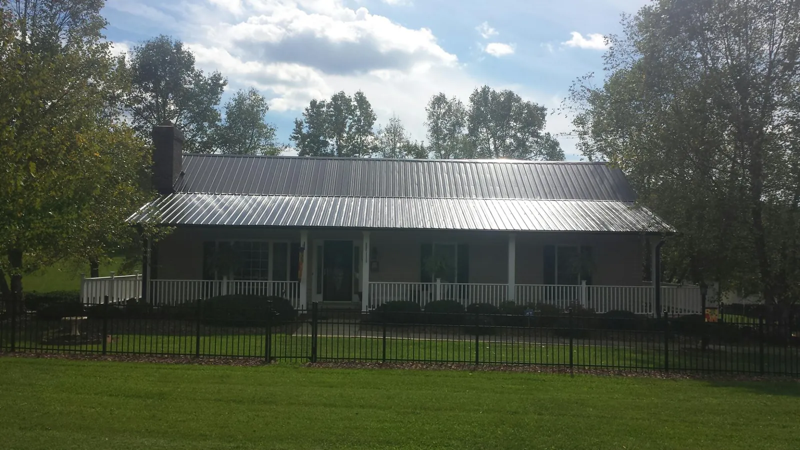 Gray metal roof on a brick ranch with a full width front porch — Gutter Guard Installation work by our crew in Mountain Lakes