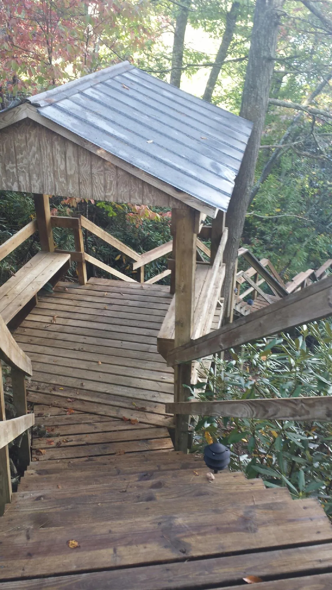Metal roofed shelter over wooden steps on a wooded walkway — Skylight Repair & Installation work by our crew in Mountain Lakes