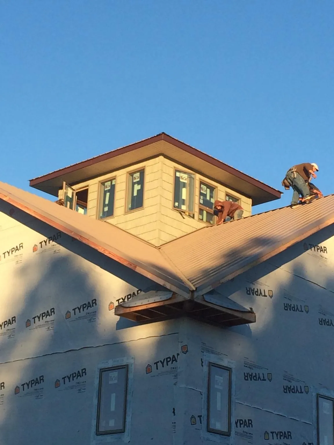 Roofers working around a rooftop cupola on a new metal roof at sunset — Roof Waterproofing in Mountain Lakes by Roofing Brothers